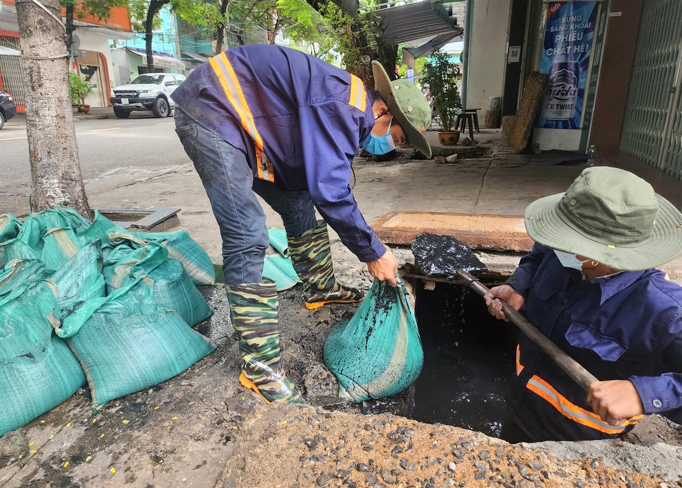 Những bao bùn đen kịt, rác bẩn được lôi lên từ cống thải. Trên đường Ông Ích Khiêm, nhiều tốp công nhân đã lật nắp cống, nạo vét một khối lượng lớn bùn đen, rác thải để thông dòng chảy.