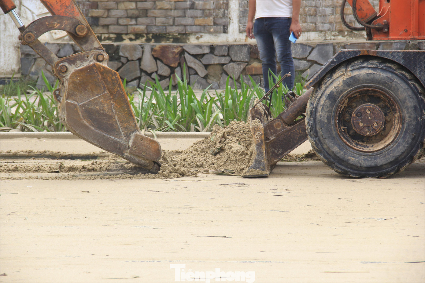 Thậm chí huy động cả xe múc. Các công nhân cho hay sau khi cào cát sẽ xịt nước để cát trôi, trả lại mặt đường sạch sẽ.