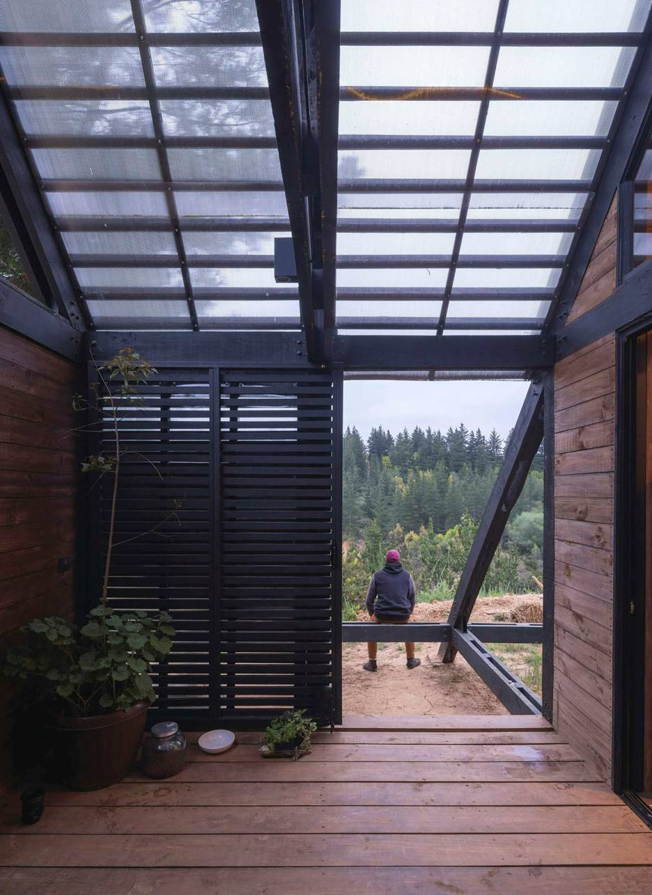 Các mặt bên của ngôi nhà mở rộng tầm nhìn ra rừng, với hệ lam gỗ như lớp rèm nhẹ, tạo sự thông thoáng và riêng tư linh hoạt.