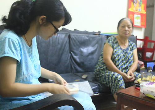 Nguyễn Hoàng Cúc - con gái ông Nguyễn Thanh Long, em gái Katerina - đang xếp lại những bức hình chị hồi nhỏ. Bên cạnh là bà Nguyễn Thùy Liên, vợ ông Long. Ảnh: Minh Thùy