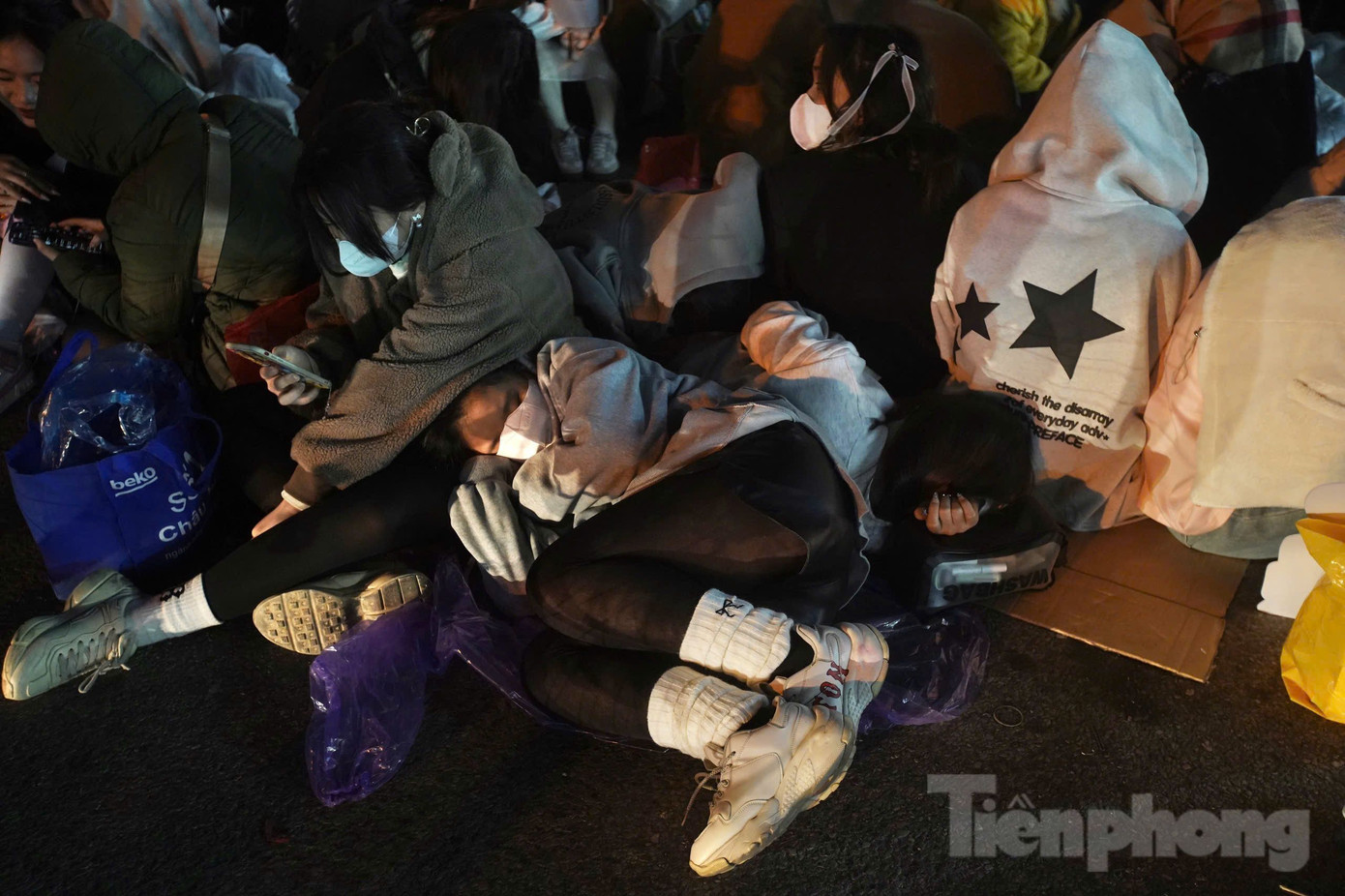 Cảnh tượng khán giả vật vã, nằm co rút giữa lề đường. Họ tạm chợp mắt sau khi xếp hàng xong, bên dưới lót áo mưa tạm bợ.