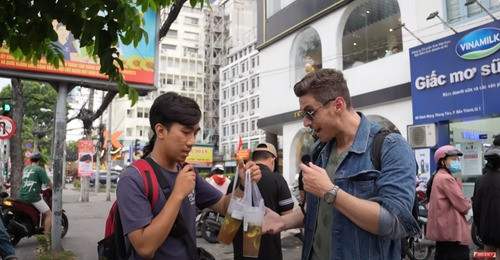 Vị khách Tây tranh thủ trò chuyện cùng một số khách hàng khác khi xếp hàng chờ mua trà chanh giã tay (Ảnh chụp màn hình)