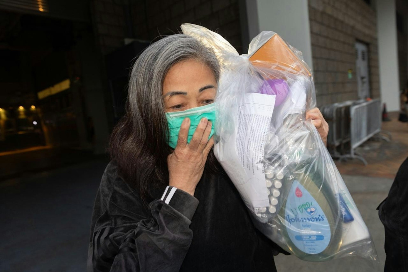 Lý Thụy Hương ôm đồ đạc cá nhân, đeo khẩu trang che kín mặt, nhanh chóng lên taxi cùng cháu trai sau 15 tháng bị tạm giam. Ảnh: HK01.