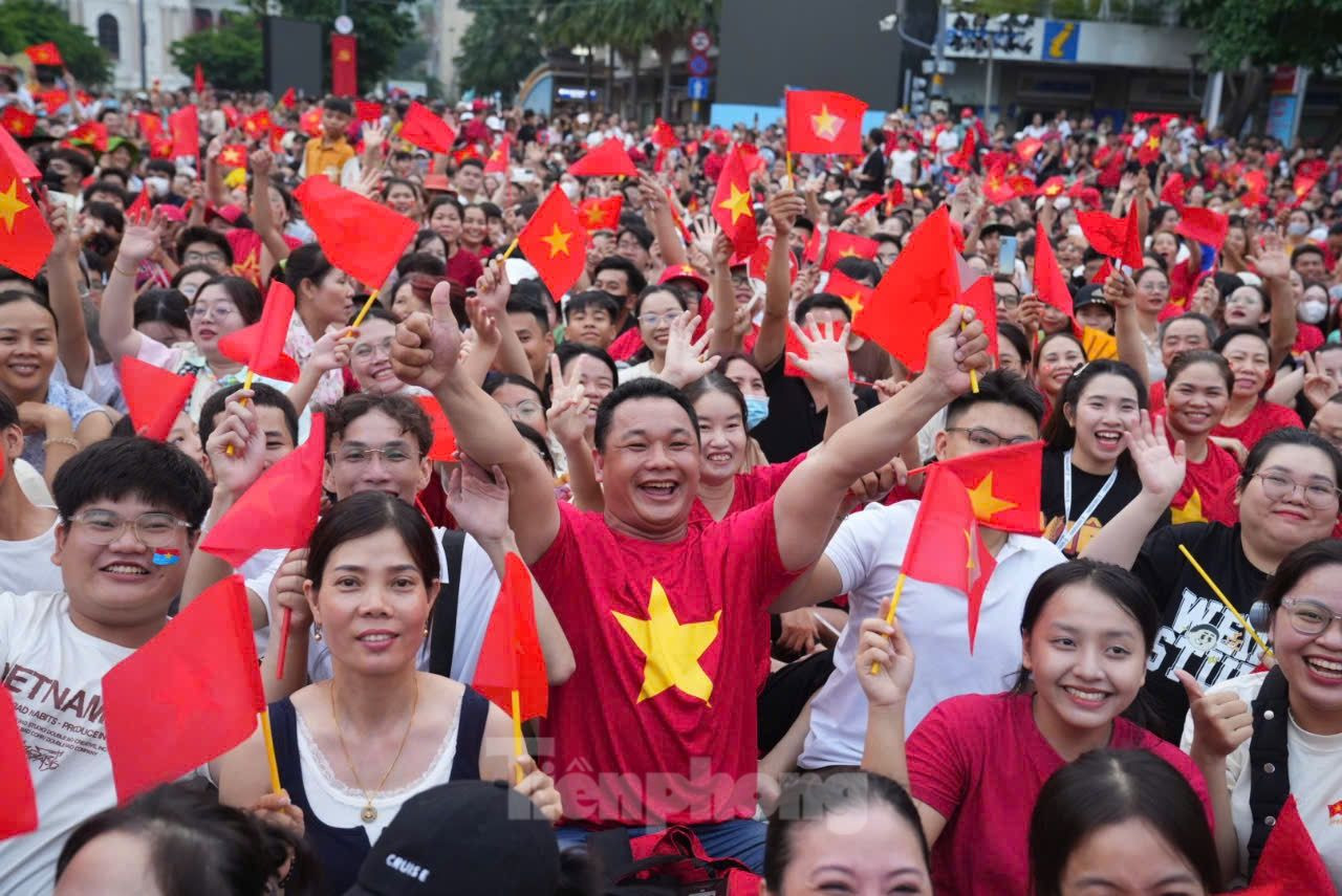 Bên cạnh cụ là những thanh thiếu niên rạng rỡ trong áo cờ đỏ, không ngừng reo vang lời ca quen thuộc: Như có Bác Hồ trong ngày vui đại thắng, Tiến về Sài Gòn, Bác đang cùng chúng cháu hành quân... Những giai điệu ấy hòa trong tiếng trống, tiếng nhạc quân hành, tạo nên không gian lễ hội vừa hùng tráng vừa đậm chất dân tộc.