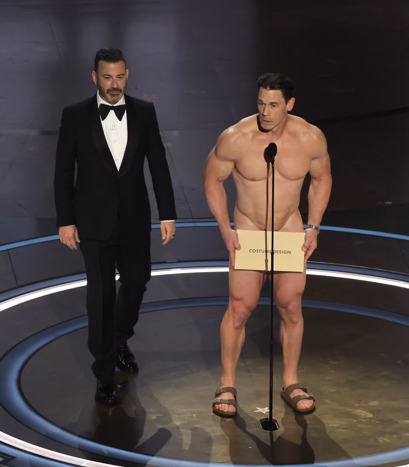 Cựu đô vật John Cena gây sốc khi có khoảnh khắc khỏa thân trên sóng trực tiếp lễ trao giải Oscar 2024. Anh công bố các đề cử cho giải Thiết kế trang phục đẹp nhất. Ảnh: Getty.