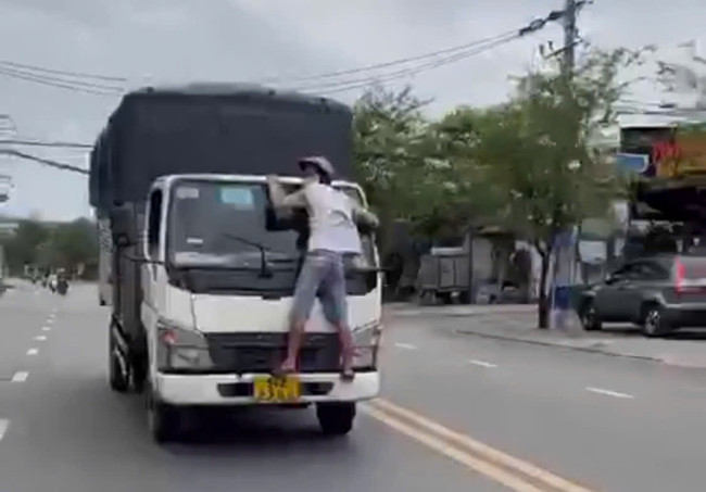 Người đàn ông bám trước đầu xe tải.