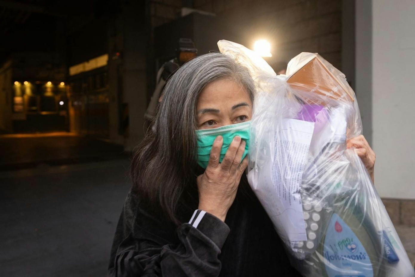 Lý Thụy Hương ôm đồ đạc cá nhân, đeo khẩu trang che kín mặt, nhanh chóng lên taxi cùng cháu trai sau 15 tháng bị tạm giam. Ảnh: HK01.