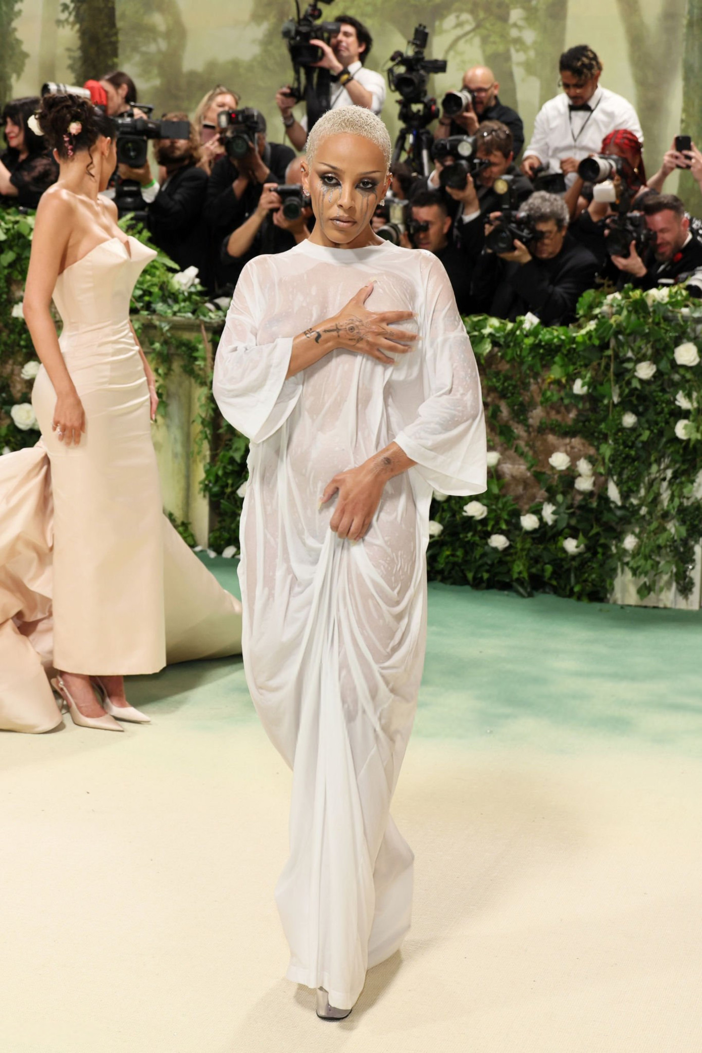 Đến Met Gala 2024, Doja Cat diện chiếc váy thấm nước, kết hợp với kiểu trang điểm chảy nước mắt, nữ ca sĩ trông như vừa bước ra khỏi phòng tắm. Trước đó trên đường đi tới sự kiện, cô gây sốc khi chỉ quấn khăn tắm.