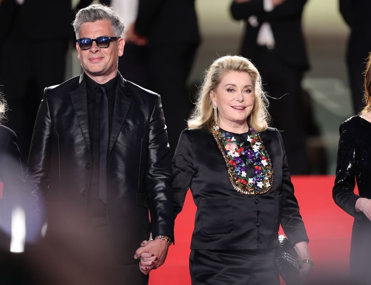 Benjamin Biolay và Catherine Deneuve nắm tay nhau đi trên thảm đỏ. Cặp sao sang trọng trong bộ trang phục ton-sur-ton.