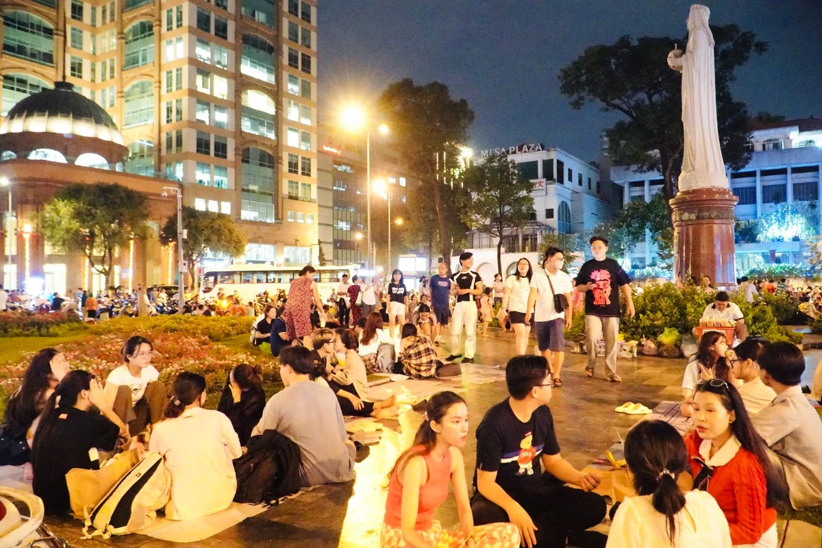 Mọi người trải thảm ngồi tán gẫu, chụp ảnh chật kín tại khuôn viên trước nhà thờ.