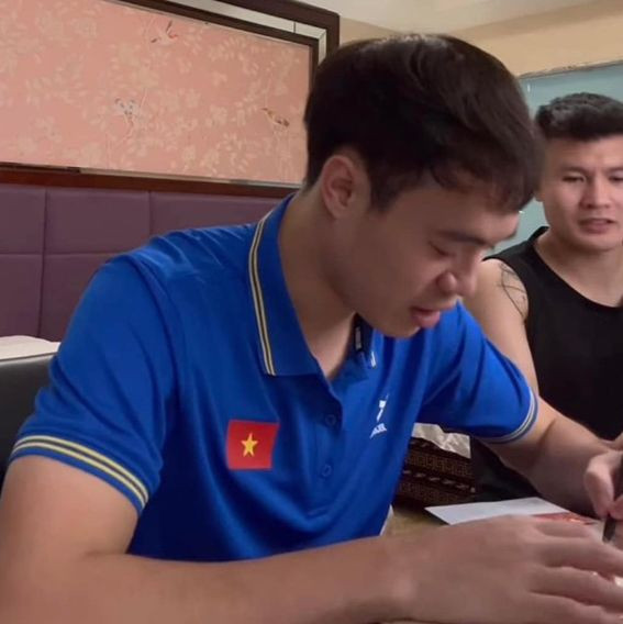 Tranh thủ thời gian rảnh rỗi đợt tập trung trên tuyển Việt Nam, Quang Hải nhờ Văn Toàn viết thiệp mời cưới. Hôm 23/3, Văn Toàn đăng tải video ngồi nắn nót từng nét chữ bên cạnh đàn em và gọi đây là "công việc làm thêm buổi tối". Ảnh: FBNV.