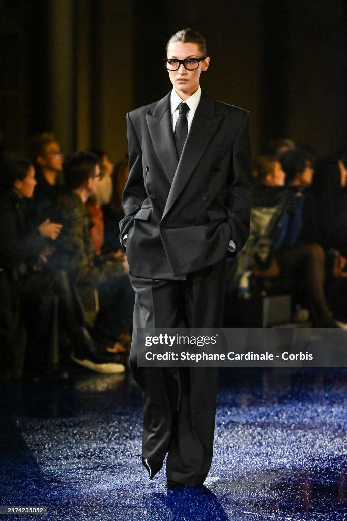 Đã hai năm kể từ lần cuối Bella Hadid sải bước trên sàn diễn. Siêu mẫu sải bước cùng đội hình Saint Laurent SS25 của Anthony Vaccarello. Trong bộ vest quyền lực rộng thùng thình, búi tóc vuốt ngược và cặp kính gọng đen dày, tạo hình của cô như vừa bước ra khỏi bộ phim mật vụ thập niên 1990. Ảnh: Getty. Đã hai năm kể từ lần cuối Bella Hadid sải bước trên sàn diễn. Siêu mẫu sải bước cùng đội hình Saint Laurent SS25 của Anthony Vaccarello. Trong bộ vest quyền lực rộng thùng thình, búi tóc vuốt ngược và cặp kính gọng đen dày, tạo hình của cô như vừa bước ra khỏi bộ phim mật vụ thập niên 1990. Ảnh: Getty.