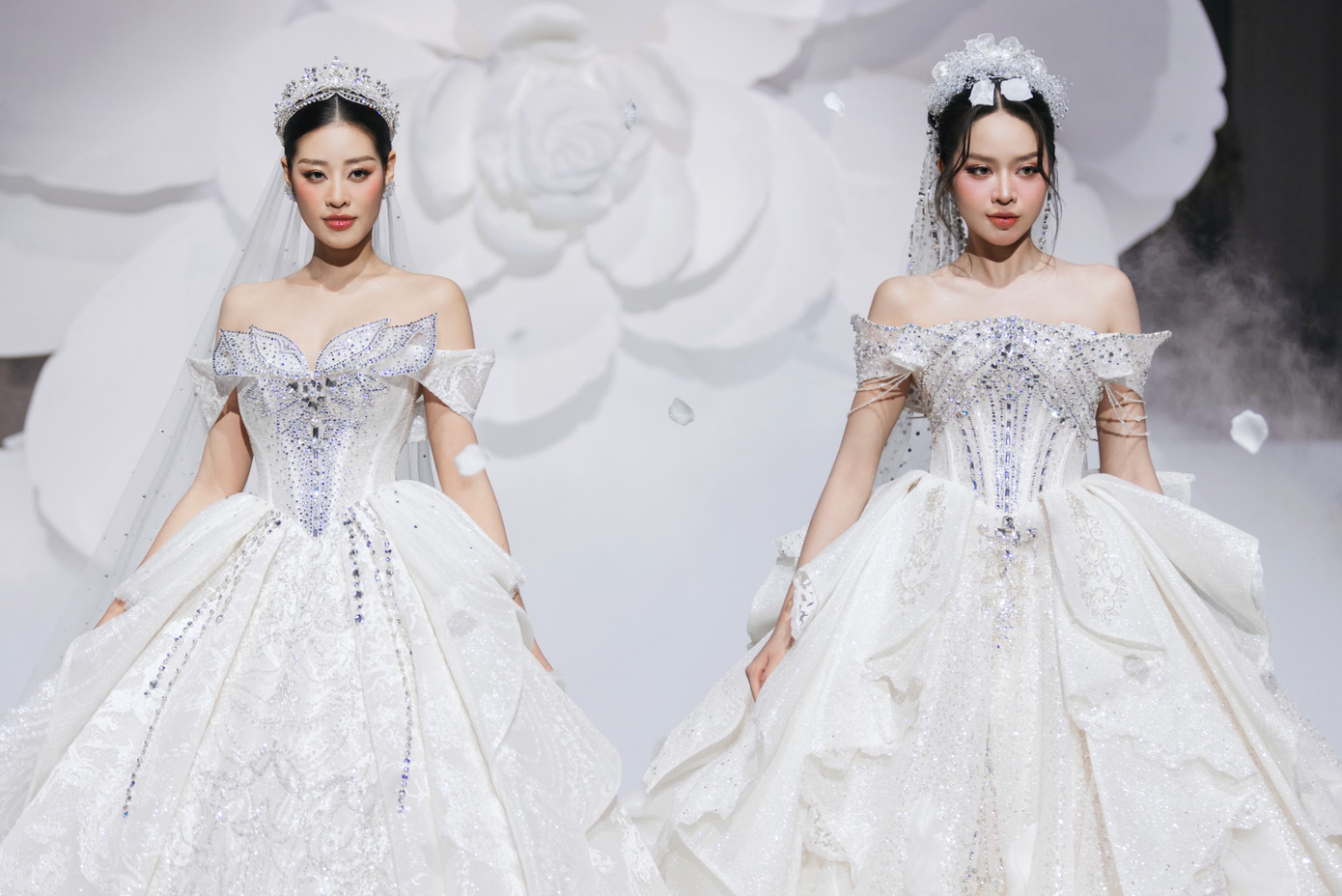 Cả hai người đẹp trình diễn trong thiết kế váy xòe trễ vai với chất liệu bắt sáng và chi tiết kim sa nổi bật. Phụ kiện như vương miện cô dâu và khăn voan đính đá Swarovski giúp hoàn thiện hình ảnh lộng lẫy, gợi liên tưởng đến những nàng công chúa cổ tích.