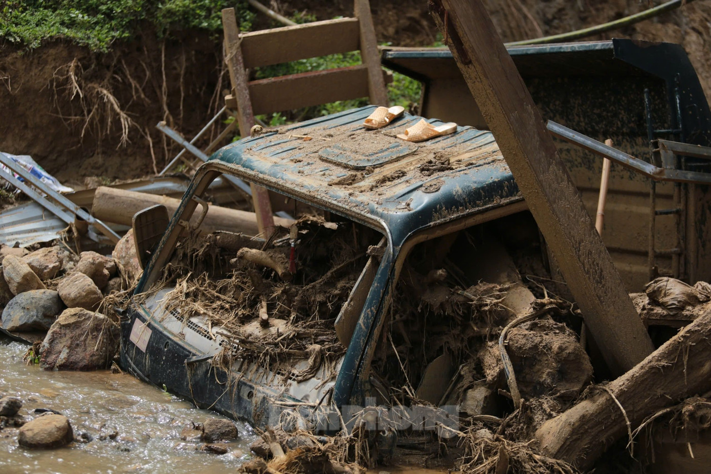 Chiếc xe tải nay chỉ còn là đống sắt vụn, nằm chỏng chơ giữa bùn đất, rác... Ảnh: Hân Nguyễn.