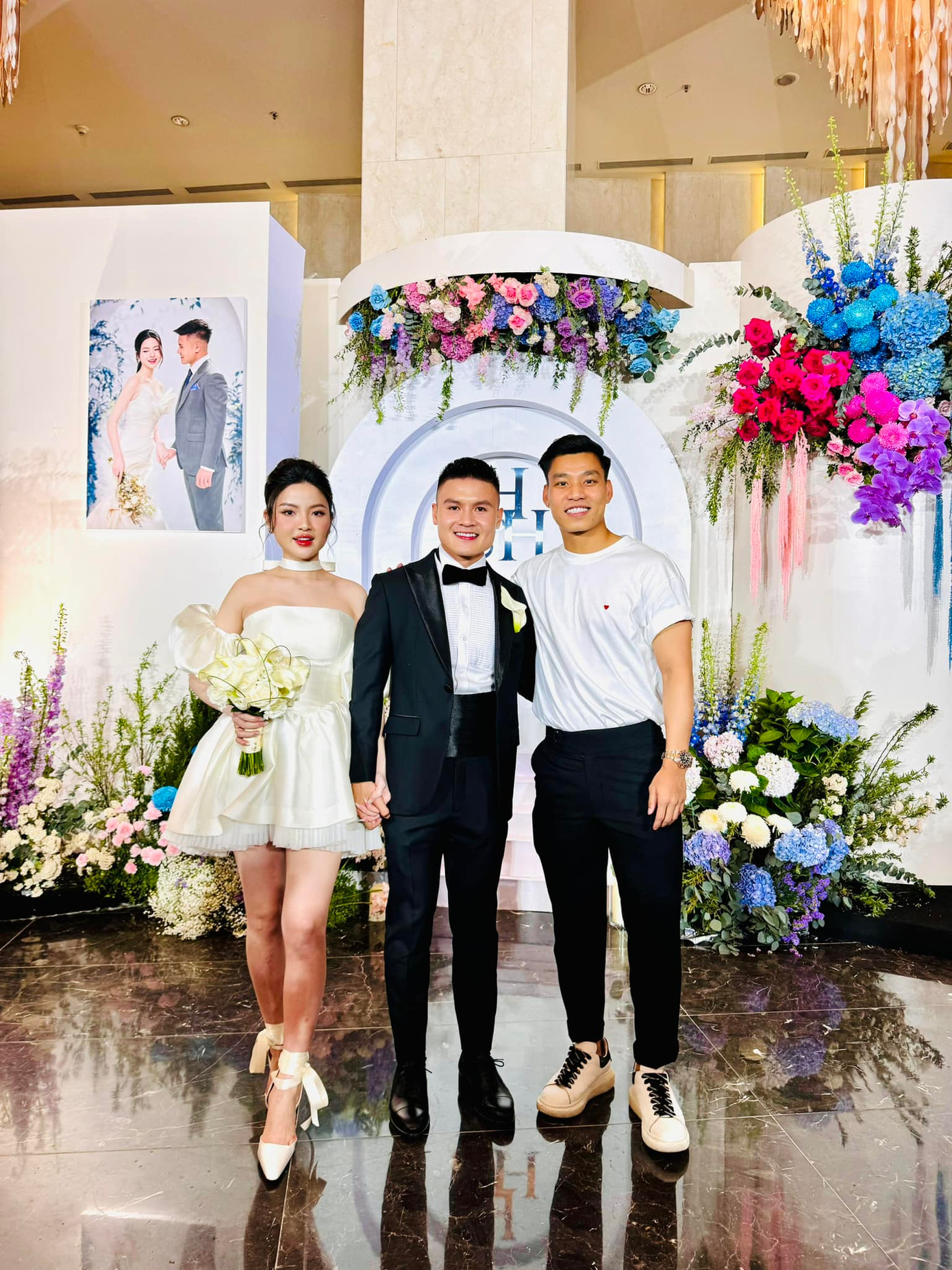 Vợ chồng Quang Hải ở after party – tiệc sau lễ cưới. Họ chụp hình cùng cầu thủ Vũ Văn Thanh. “Chúc mừng hạnh phúc hai vợ chồng, chúc 2 em hạnh phúc tới đầu bạc răng long” – Văn Thanh nhắn nhủ. Cô dâu Chu Thanh Huyền đã thay bộ váy ngắn cùng chú rể tổ chức trò chơi với khách mời. Ảnh: FBNV.