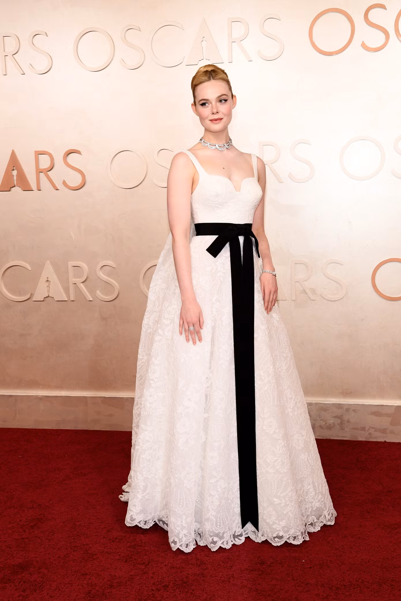 Elle Fanning tiếp tục khẳng định gu thời trang tinh tế với một thiết kế cổ điển từ Givenchy. Nữ diễn viên A Complete Unknown khoác lên mình chiếc váy ren dáng chữ A, kết hợp cùng vòng cổ kim cương lấp lánh. Điểm nhấn ấn tượng chính là chiếc nơ dài thướt tha gần chạm đất, tạo sự tương phản độc đáo và làm nổi bật vẻ đẹp thanh thoát trên thảm đỏ.