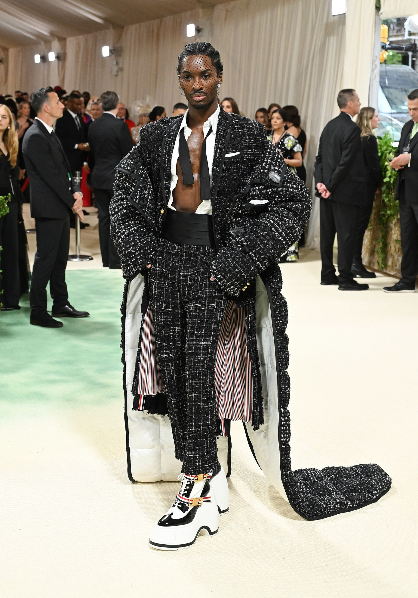 Alton Mason mặc chiếc áo khoác đuôi tôm bằng vải tuýt denim màu đen kết hợp với áo khoác và váy xếp li bằng vải tuýt kẻ sọc.