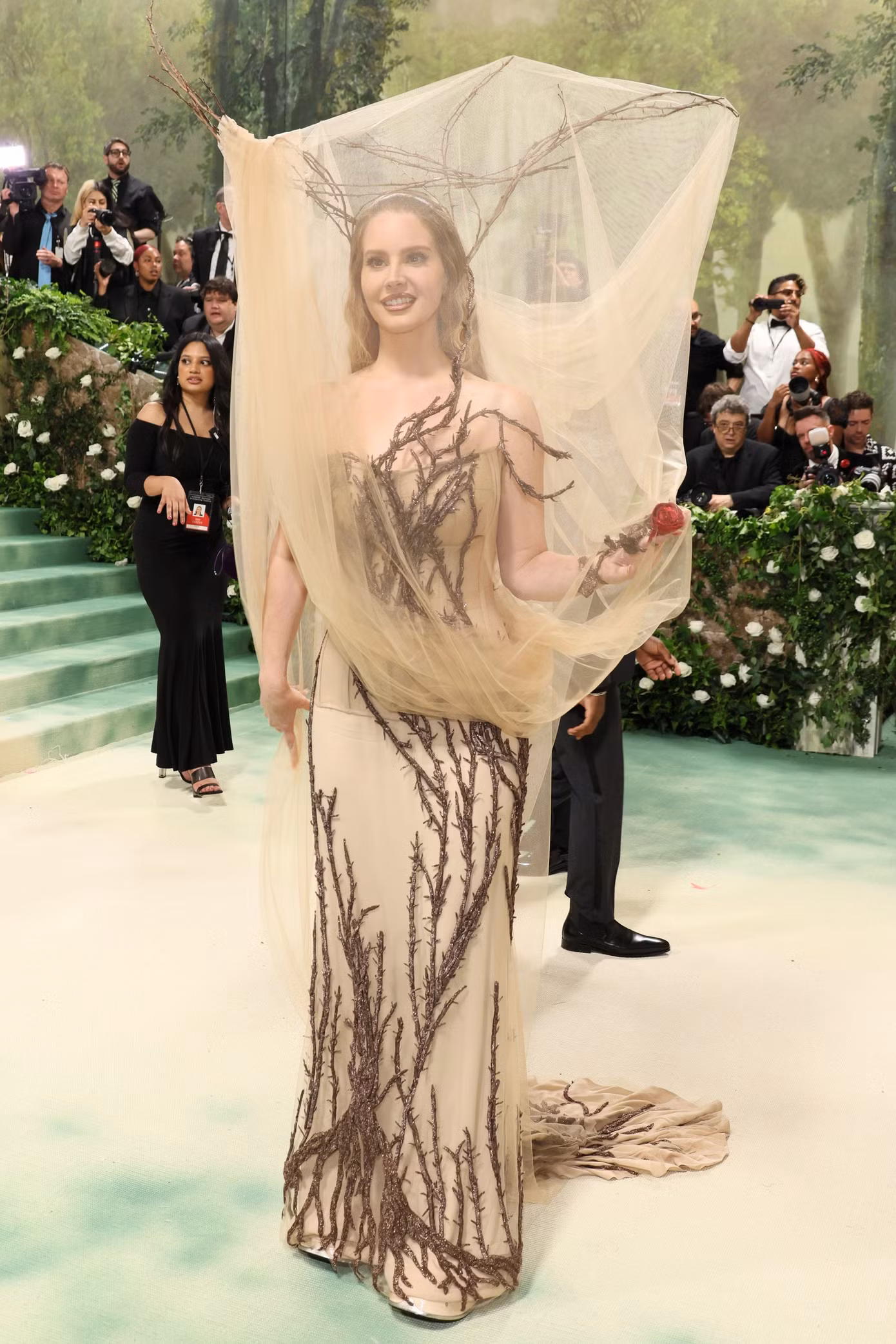 Lana Del Rey bước đi ấn tượng trên thảm đỏ. Vogue nhận xét nữ ca sĩ mang điểm nhấn với phong cách thanh tao, đen tối nhưng không kém phần lãng mạn. Met Gala 2024 đánh dấu lần đầu Lana Del Rey tham dự kể từ năm 2018.