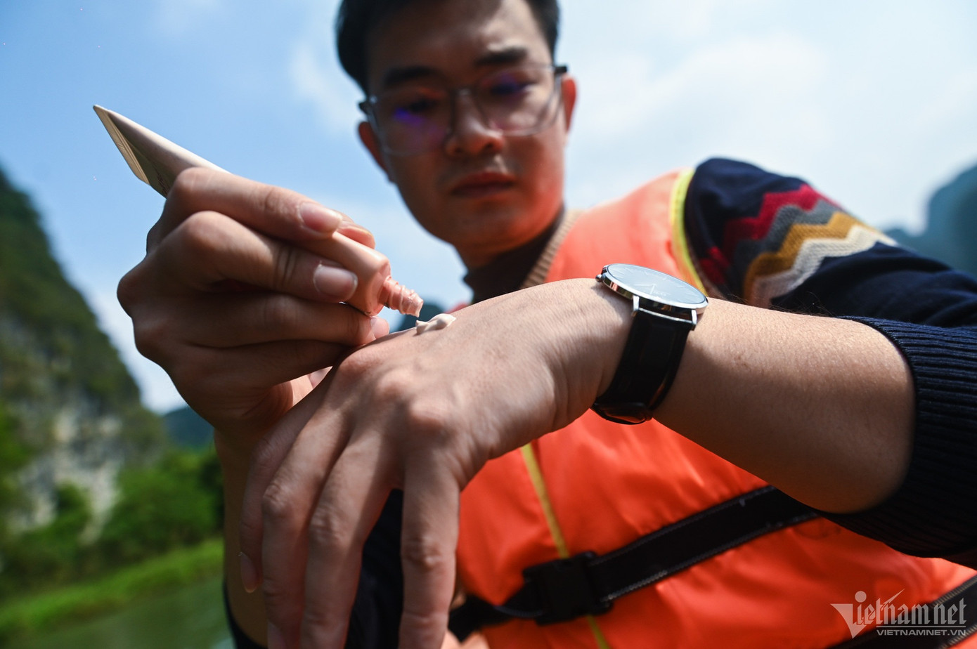 Nam du khách đến từ Hà Nội thoa kem chống nắng trong thời gian ngồi thuyền tham quan cảnh sắc Tràng An. &quot;Tôi và bạn chủ đích mang kem chống nắng vì biết hôm nay nhiệt cao. Trước khi xuống thuyền chúng tôi còn để lại áo khoác ở xe, chỉ mặc trang phục thoáng mát&quot;, anh nói.