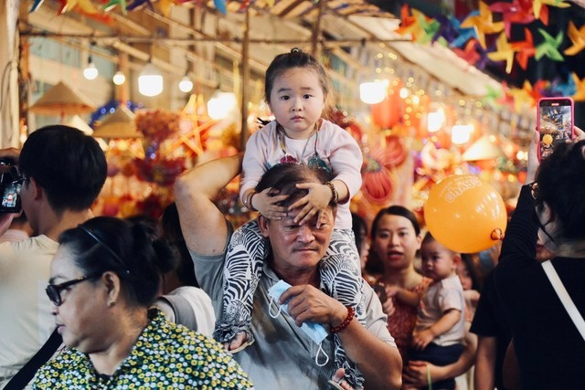 Các em nhỏ được cha mẹ, ông bà cõng trên vai để đi tham quan, chụp ảnh tại Phố lồng đèn.