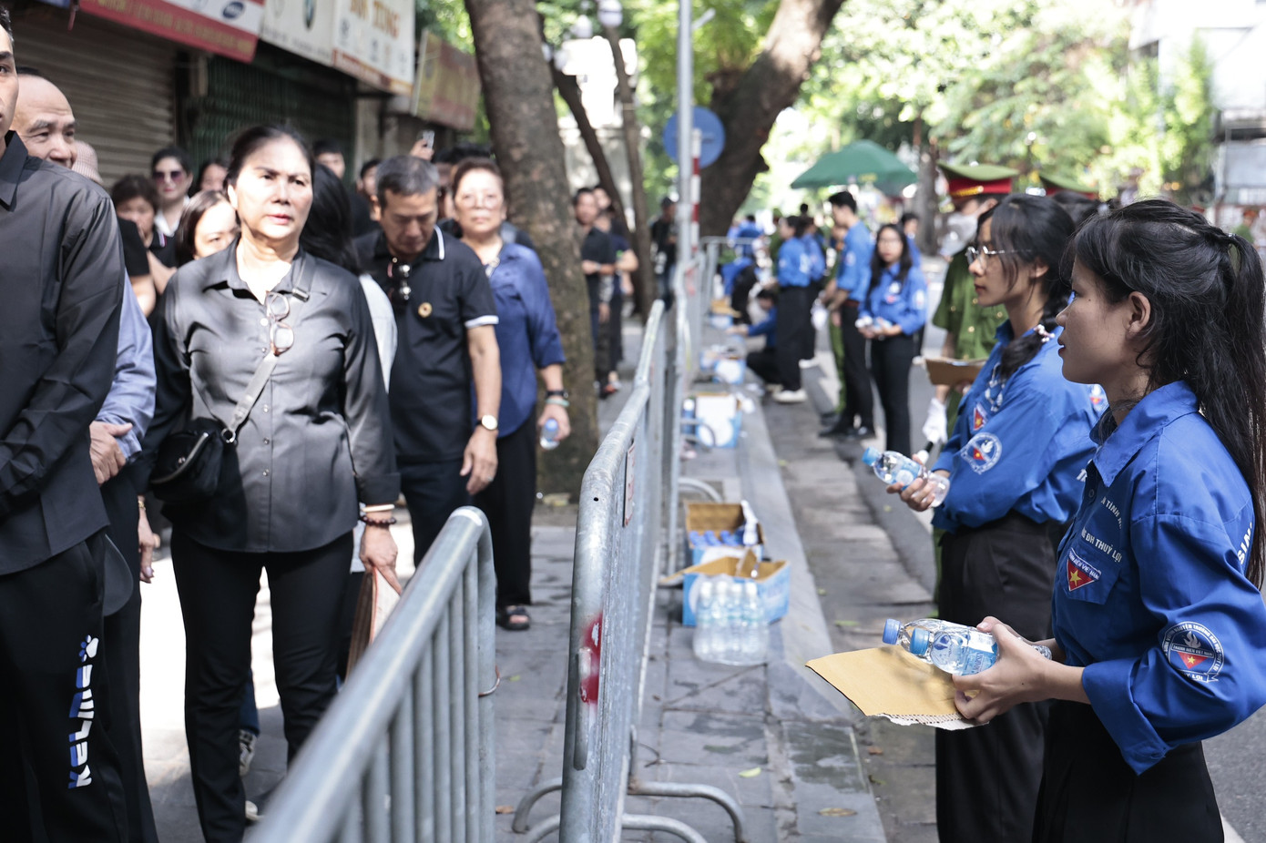 Từ phía ngoài cổng an ninh, các tình nguyện viên phối hợp với các lực lượng hỗ trợ nhân dân đến viếng, cung cấp nước, quạt giấy....