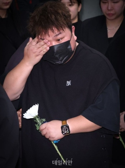 Ca sĩ Huh Gak lau nước mắt, trong tay cầm hoa cúc trắng tiễn biệt Park Bo Ram.