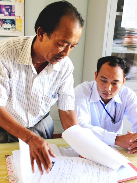 Ông Nguyễn Văn Cồn với chồng hồ sơ tồn đọng, thiếu dấu đỏ ở Hoàng Sa từ cuối 2010 tới nay. Ảnh: Nam Cường