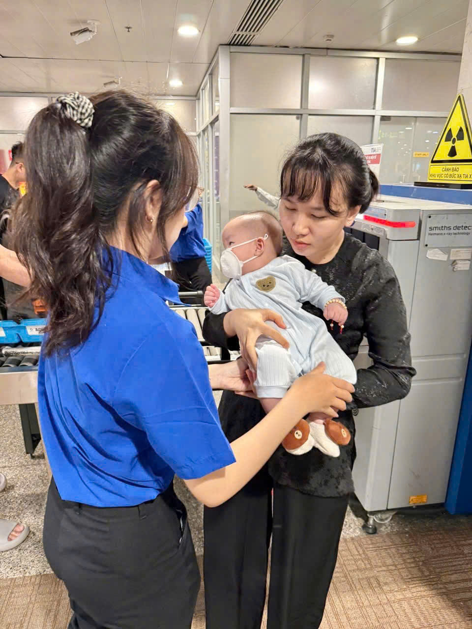 Các bạn đoàn viên thanh niên trông giữ trẻ để người thân làm thủ tục qua cửa an ninh soi chiếu.