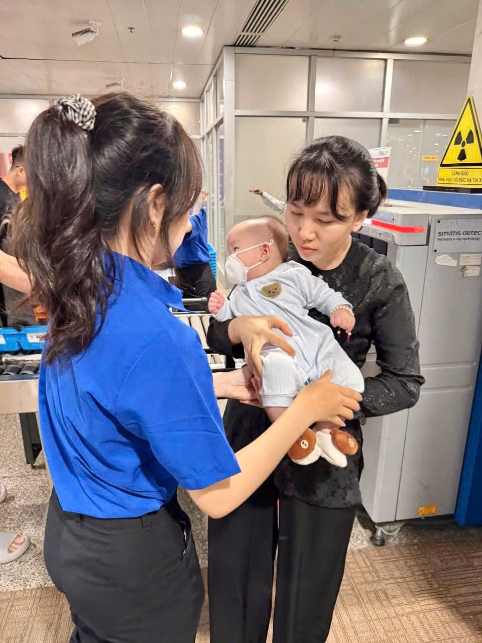 Các bạn đoàn viên thanh niên trông giữ trẻ để người thân làm thủ tục qua cửa an ninh soi chiếu.