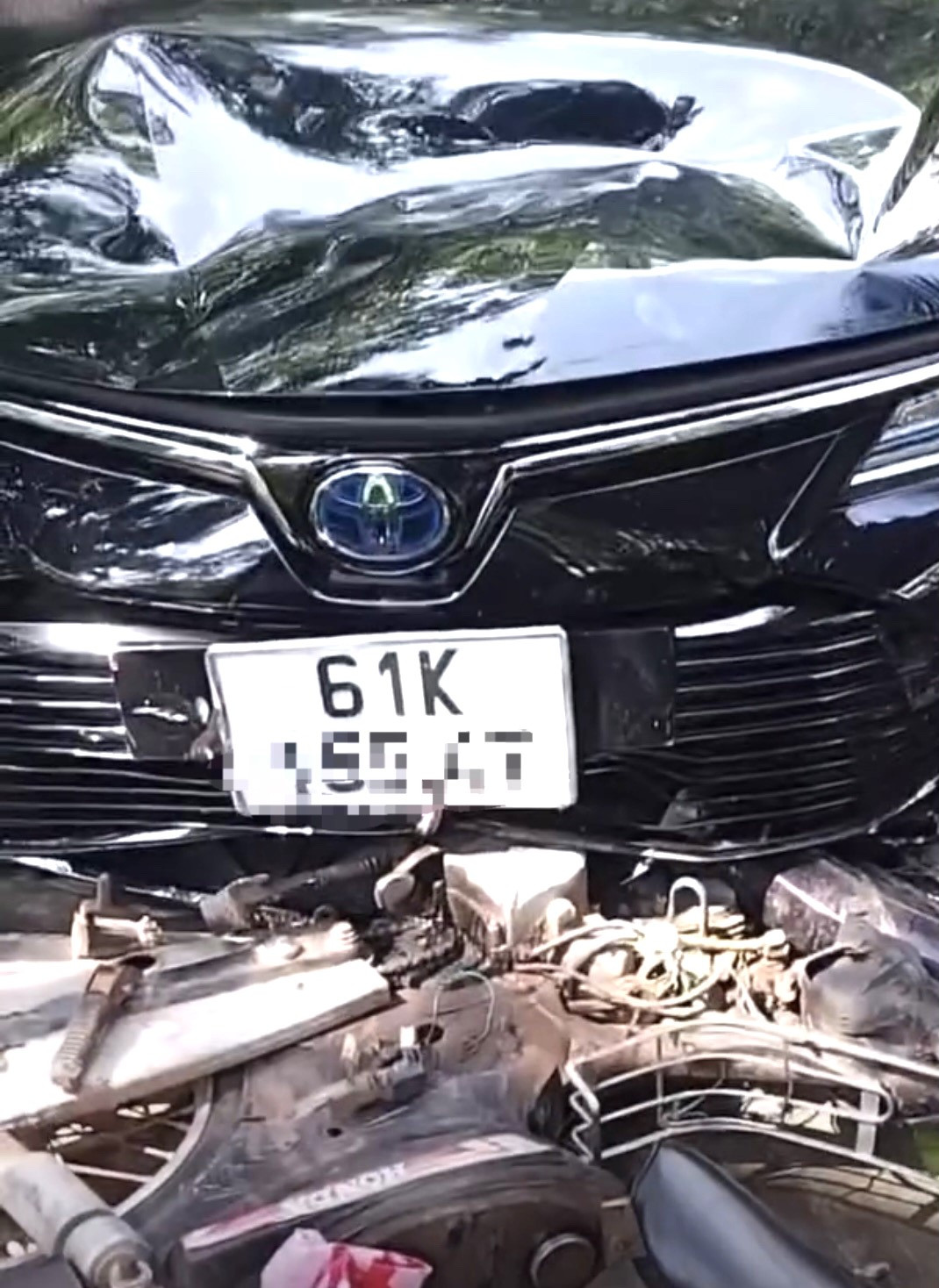 Xe máy bị mắc kẹt dưới gầm trước ô tô