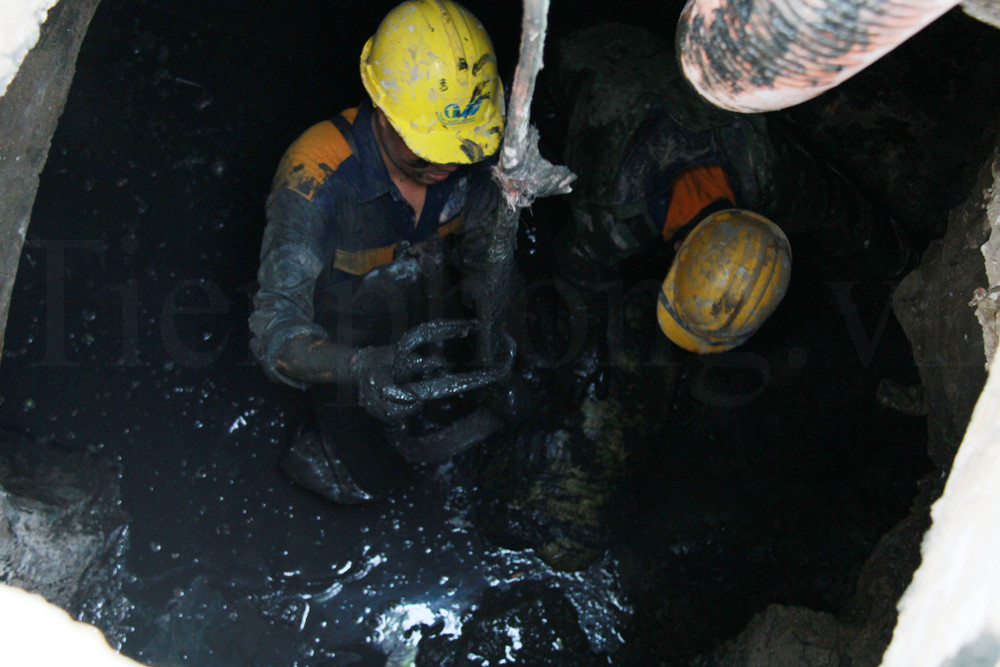 Dây tời được chuyển xuống để vận chuyển các bao tải xi măng lên trên mặt đường. Ảnh: Trường Phong