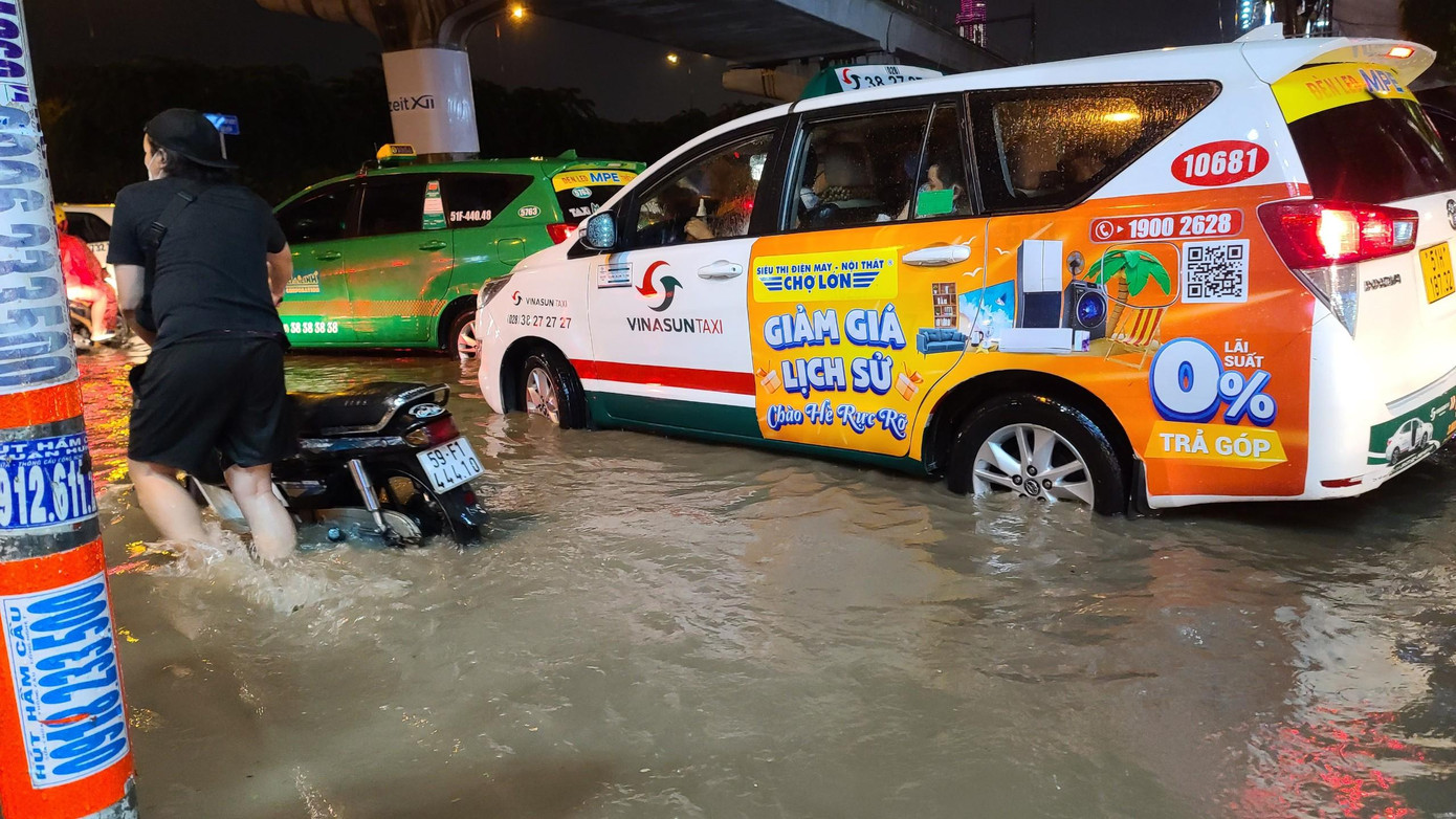 Nhiều phương tiện "chết máy" do ngập nước, người dân phải bì bõm lội nước đưa phương tiện thoát khỏi điểm ngập úng. Ảnh: CTV