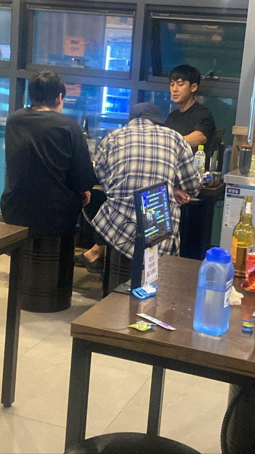 Bức ảnh chứng minh được cô bạn chia sẻ, do một bạn làm cùng chụp lại. Mingyu mặc áo đen ngồi trong một mình, Jung Kook mặc áo đen, quay lưng và Cha Eun Woo mặc sơmi caro.