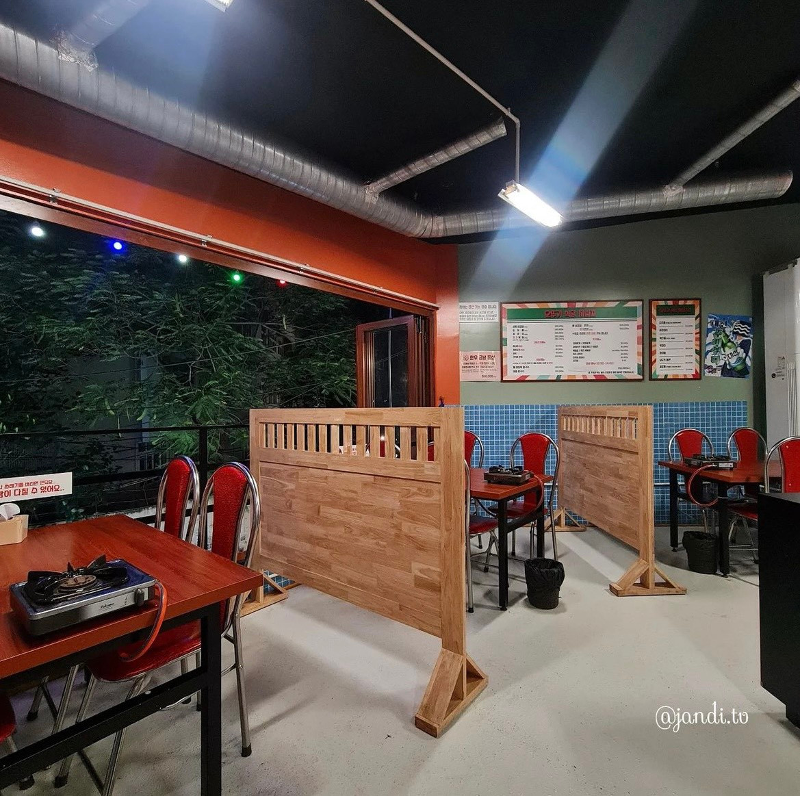 Bàn ăn và ghế quán sử dụng màu gỗ nâu đỏ, giữa các bàn được ngăn bằng một tấm chắn nhỏ bằng gỗ tạo sự riêng tư. - Ảnh: Instagram jandi.tv Bàn ăn và ghế quán sử dụng màu gỗ nâu đỏ, giữa các bàn được ngăn bằng một tấm chắn nhỏ bằng gỗ tạo sự riêng tư. - Ảnh: Instagram jandi.tv