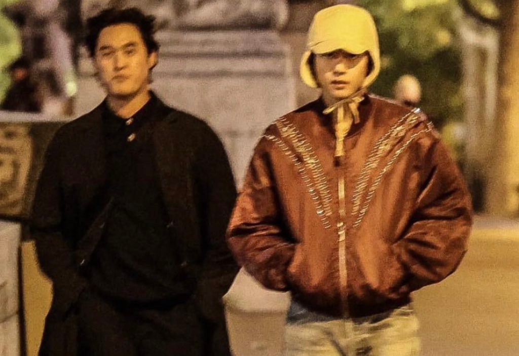 V mặc trang phục y hệt trong clip đi cùng quản lý. V mặc trang phục y hệt trong clip đi cùng quản lý.