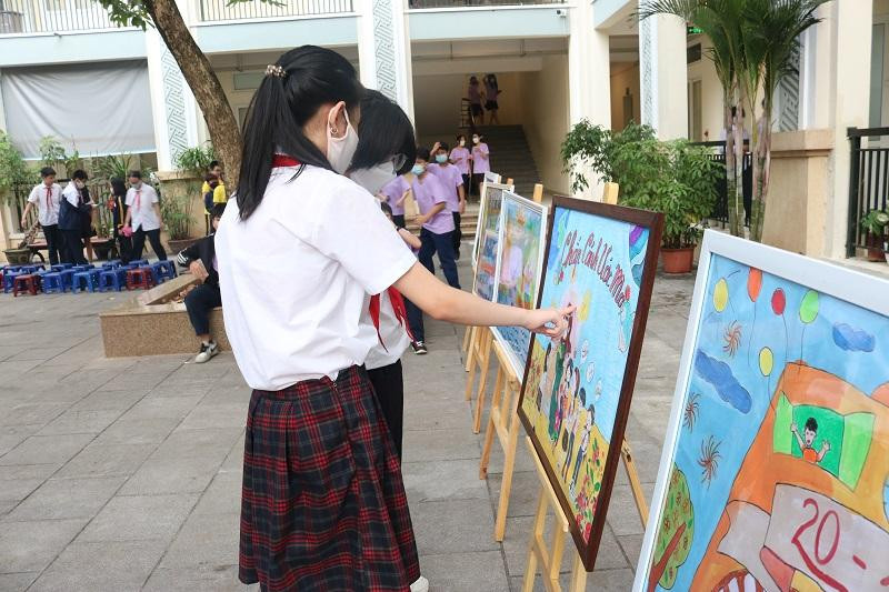 Một vài học sinh tranh thủ ngắm nhìn các bức vẽ được trưng bày hai bên sân khấu.