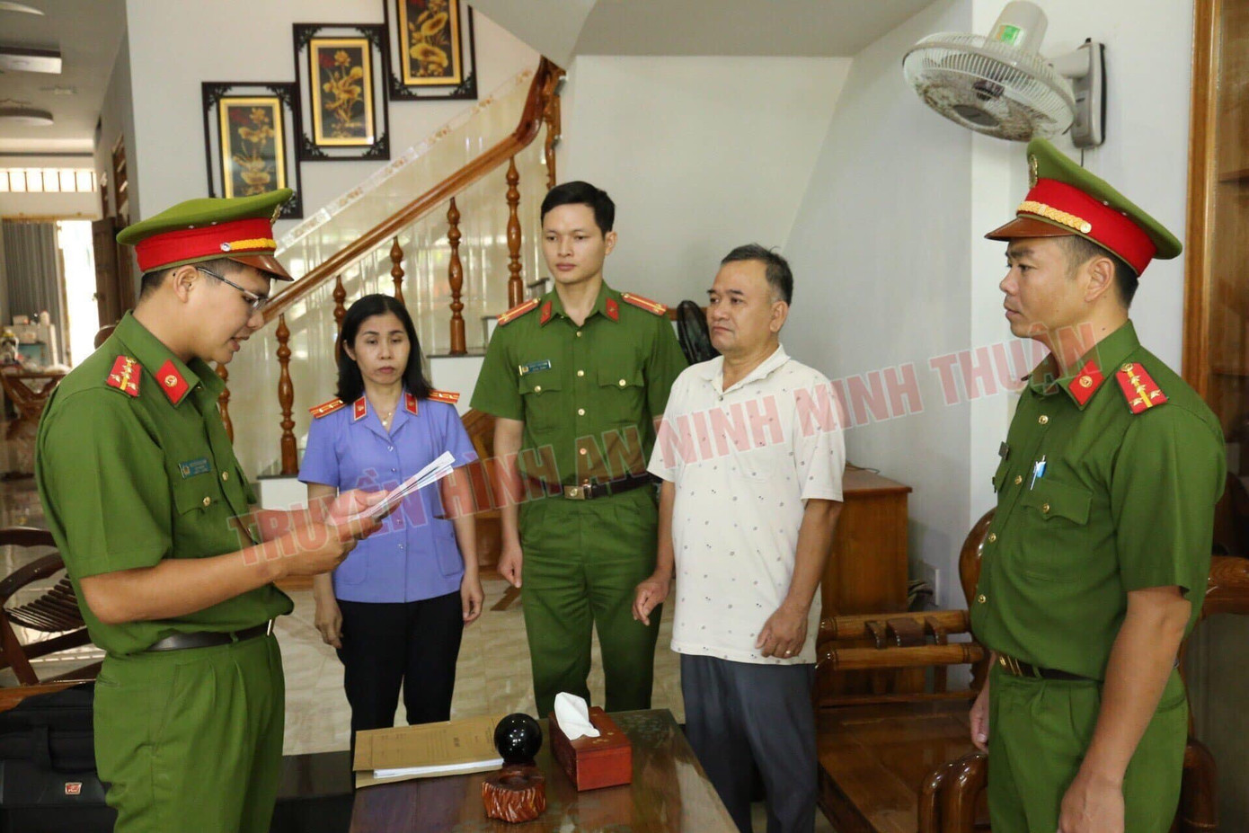 Công an tống đạt quyết định khởi tố đối với Giám đốc Trung tâm đăng kiểm xe cơ giới 85-02D Lê Tự Trị (áo trắng). Ảnh: ANTV Ninh Thuận.