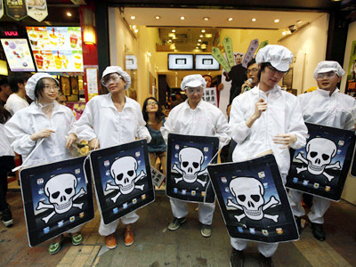 Sinh viên Trung Quốc ăn mặc giống công nhân Foxconn, mang hình ảnh máy tính bảng iPad với hình đầu lâu đứng trước cửa hàng của Apple ở Hong Kong. Ảnh: AP. Sinh viên Trung Quốc ăn mặc giống công nhân Foxconn, mang hình ảnh máy tính bảng iPad với hình đầu lâu đứng trước cửa hàng của Apple ở Hong Kong. Ảnh: AP