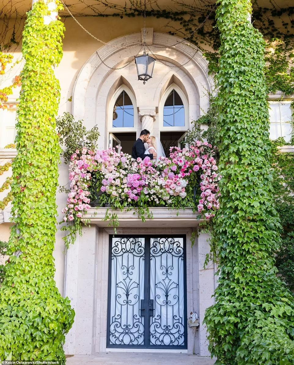 Đôi tân hôn trao nhau nụ hôn ngọt ngào trên ban công biệt thự, cũng được trang trí bằng hoa hồng kỳ công.