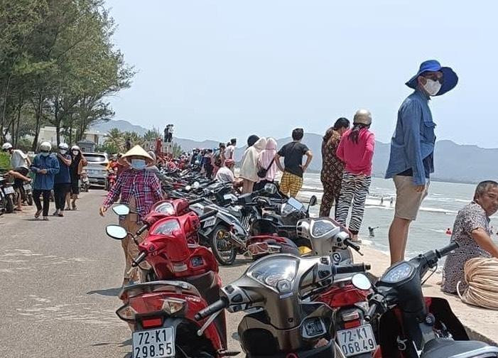 Người dân tụ tập trên bờ xem lực lượng chức năng tìm kiếm thi thể một nạn nhân bị sóng đánh trôi xuống biển.