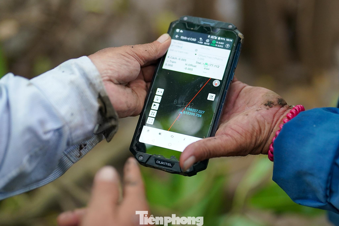 Công nhân đang xác định vị trí các mốc cắm cọc trên điện thoại.