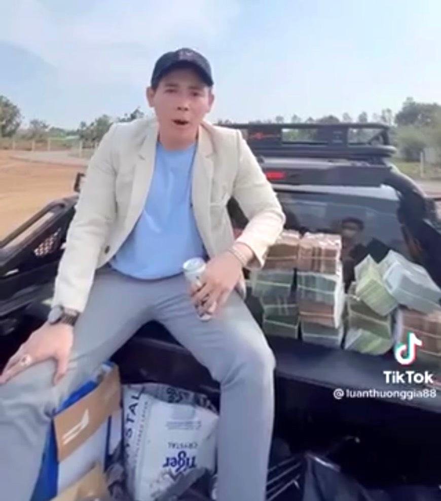 Nam thanh niên mặc vest màu trắng, đầu đội mũ, ngồi sau xe ô tô bán tải, liên tục xếp những cọc tiền có mệnh giá 500 ngàn đồng, 200 ngàn đồng. Nam thanh niên mặc vest màu trắng, đầu đội mũ, ngồi sau xe ô tô bán tải, liên tục xếp những cọc tiền có mệnh giá 500 ngàn đồng, 200 ngàn đồng.