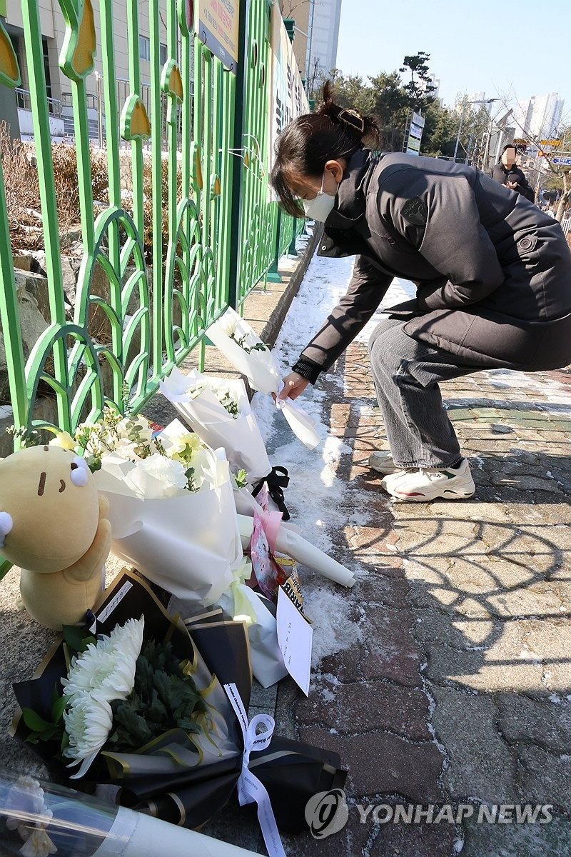 Nhiều người đến cổng trường tiểu học đặt hoa để tưởng niệm nữ sinh xấu số. (Ảnh: Yonhap)
