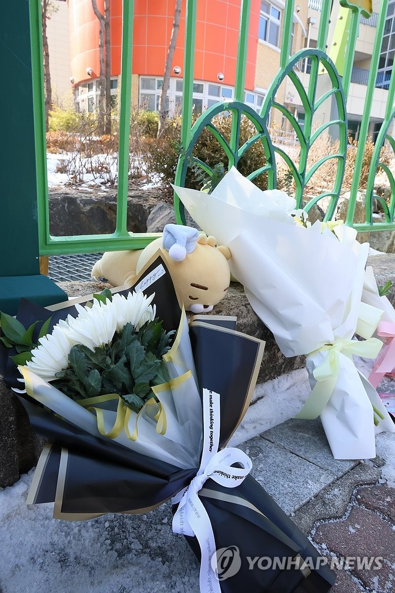 Nhiều người đến cổng trường tiểu học đặt hoa để tưởng niệm nữ sinh xấu số. (Ảnh: Yonhap)