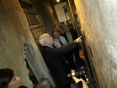 Cựu ứng cử viên Tổng thống Mỹ của đảng Cộng Hòa John McCain đọc tấm biển trước một phòng giam trong khu di tích nhà tù Hỏa Lò. Ảnh AP.