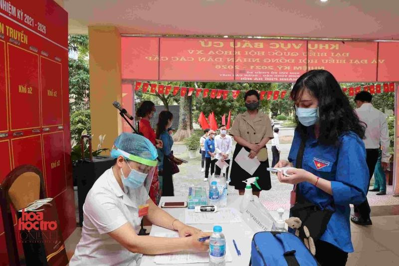 Cử tri được hướng dẫn khai báo y tế, sát khuẩn tay tại khu vực bầu cử ở Học viện Báo chí và Tuyên truyền.