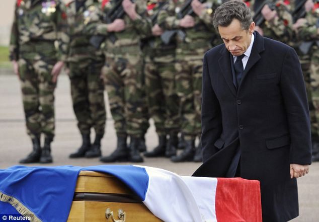 Tổng thống Pháp Nicolas Sarkozy đứng ở phía trước của một trong ba chiếc quan tài của ba binh sĩ bị giết chết bởi nghi can
