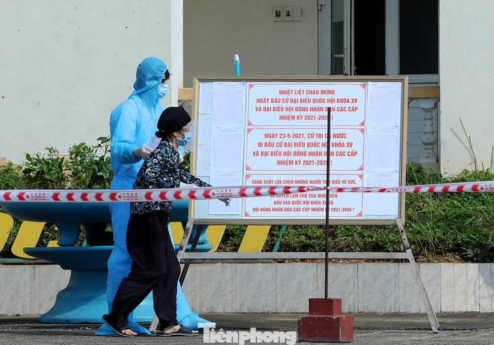 Một cử tri cao tuổi trong khu cách ly được cán bộ đưa vào khu vực bỏ phiếu