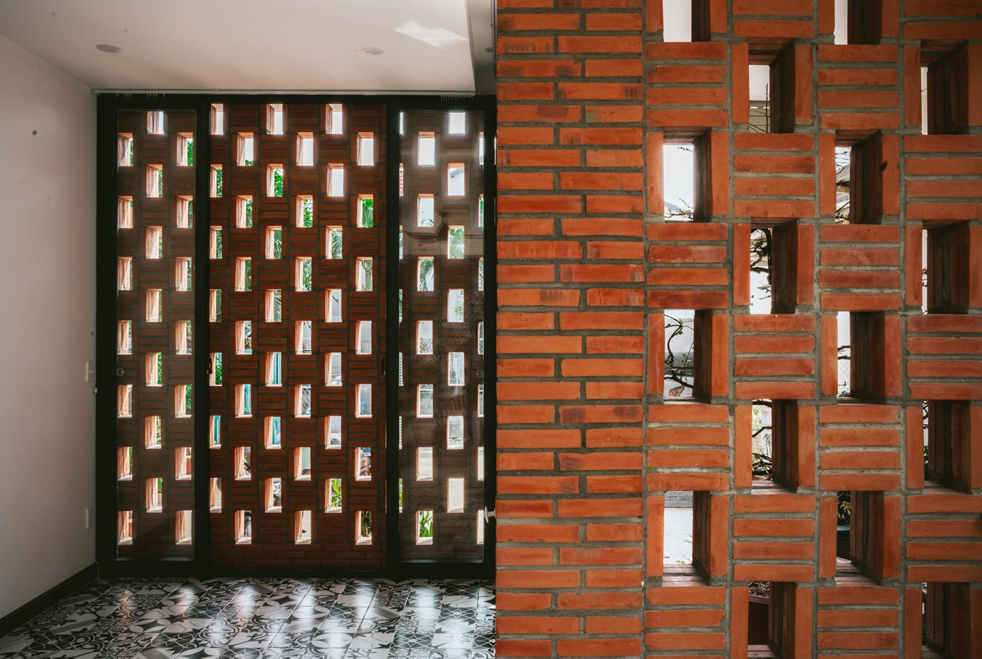 Mặt trước nhà bao gồm hai bức tường gạch với một khoảng không gian che mát lồng vào nhau, che chắn cho ngôi nhà khỏi ánh nắng trực tiếp và đón không khí trong lành vào nhà.