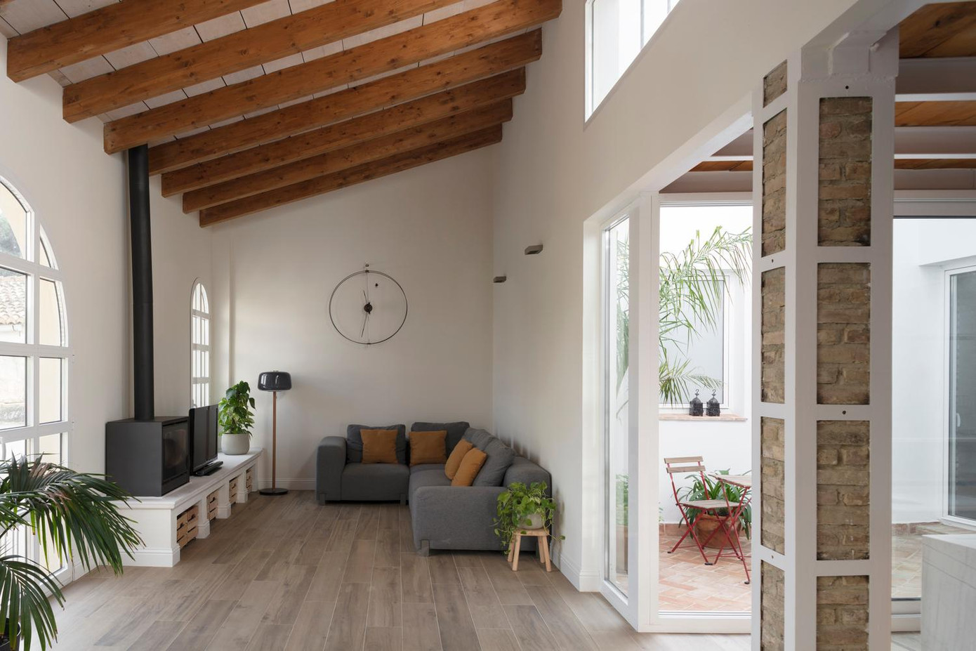 Phía sau phòng ngủ là không gian bếp và phòng khách lộ thiên, phần trần của khu vực này thấp hơn gác lửng để tạo nên các khoảng trống lưu thông không khí cho ngôi nhà.